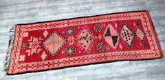 Bring timeless elegance to your home with this vintage Moroccan runner rug, a hand-knotted Berber carpet radiating old-world charm. Measuring 3.7 ft x 11.5 ft, this tribal wool rug features a striking red and black geometric design, crafted by skilled artisans using age-old techniques. The slightly distressed finish adds authenticity, making it a perfect fit for boho, rustic, or minimalist interiors. Use it as a hallway runner, kitchen accent, or layered over larger rugs for depth. The high-quality wool ens