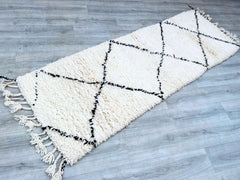 Enhance your home’s aesthetic with a vintage Moroccan runner rug, featuring timeless Beni Ourain designs in soft ivory and black. This handwoven wool carpet is perfect for hallways, kitchens, or living rooms, offering both style and comfort. The intricate tribal patterns reflect traditional Berber craftsmanship, making each piece a functional work of art. The high-quality wool ensures plush softness underfoot, while the durable weave withstands daily use. Whether you prefer a minimalist, boho, or rustic loo