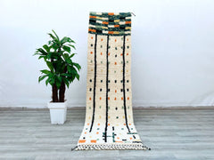 Enhance your interiors with this authentic Moroccan wool rug, a 3.2 ft x 10.4 ft vintage Berber runner that exudes rustic elegance. The Azilal design features a blend of traditional patterns and soft textures, making it a perfect fit for boho, eclectic, or minimalist styles. Handcrafted using natural dyes and wool, this Beni Ourain-style rug is both durable and luxurious, ideal for high-traffic areas like hallways or kitchens. Its neutral tones and tribal motifs create a warm, inviting atmosphere, while the