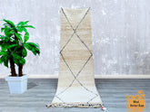 Enhance your home with this handmade Beni Ourain runner rug, a luxurious wool carpet featuring a timeless tribal Berber design. The neutral color palette and intricate patterns make it a versatile choice for boho, Scandinavian, or eclectic decor styles. Measuring 3x9 feet, this hallway runner is perfect for narrow spaces, adding warmth and texture underfoot. The high-quality wool ensures softness and durability, while the hand-knotted craftsmanship reflects Morocco’s rich weaving heritage. A sustainable, et