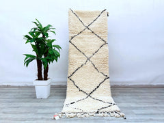 Transform your living space with an authentic Azilal Berber rug, handcrafted using traditional weaving techniques for a truly unique piece. Known for its tribal diamond patterns and soft wool texture, this Moroccan hallway runner adds a boho-chic vibe to any room. The neutral cream and black design complements various decor styles, from Scandinavian to eclectic. Made from natural, undyed wool, this handwoven carpet is both eco-friendly and durable, ideal for high-traffic areas. Whether used as a floor accen