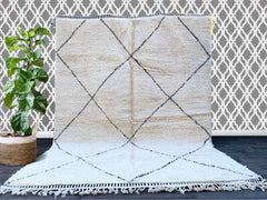 Bring the rich heritage of Moroccan craftsmanship into your home with this authentic handmade Beni Ourain rug. Woven by skilled Berber artisans using 100% natural wool, this rug features the iconic black and white geometric patterns that symbolize tribal traditions. The plush, high-pile texture adds warmth and comfort, making it perfect for living rooms, bedrooms, or cozy reading nooks. Each piece is unique, with slight variations that highlight its artisanal charm. Whether you're aiming for a boho, minimal