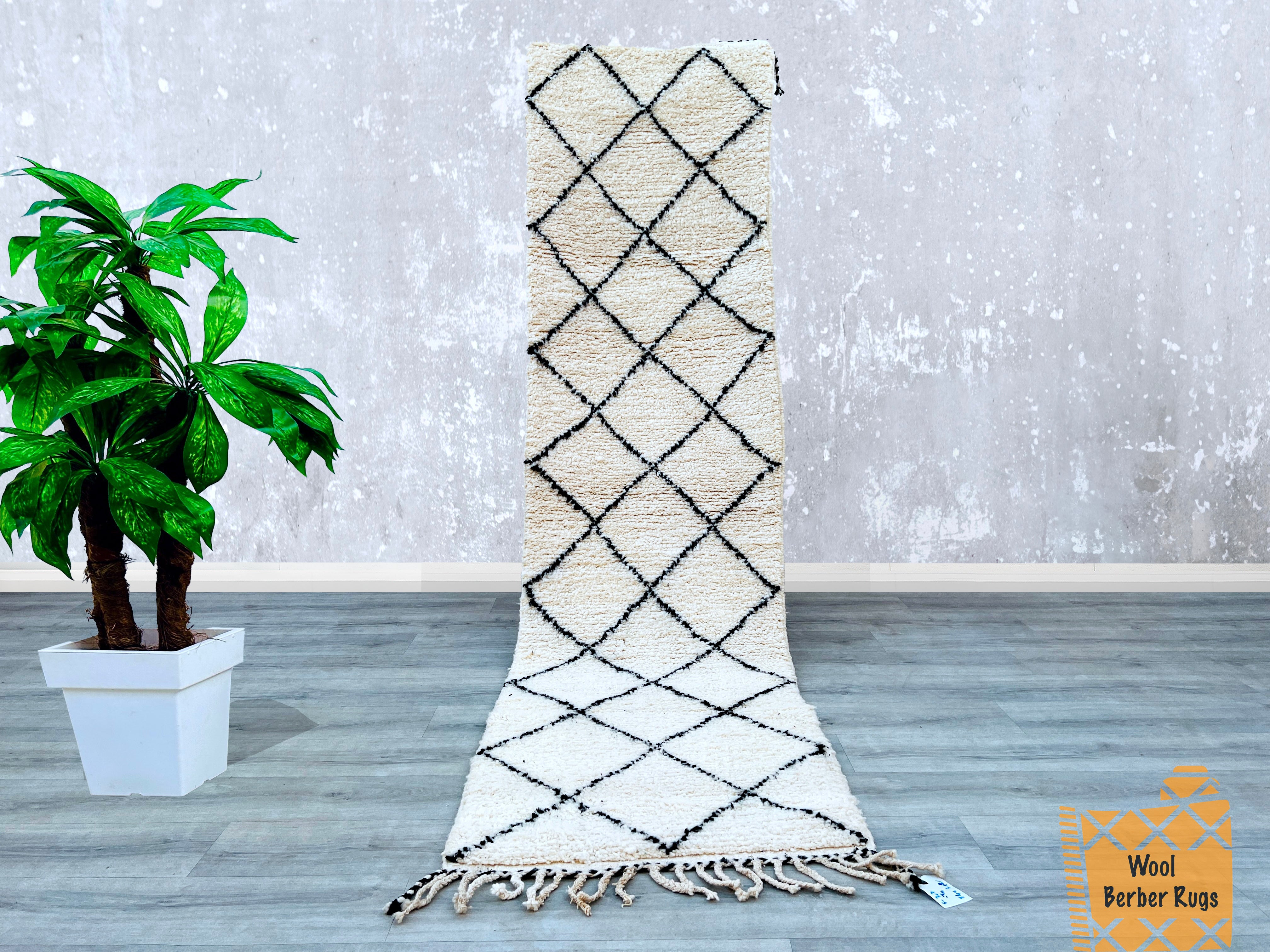 Bring authentic Moroccan charm into your home with this handmade Beni Ourain runner rug. Measuring 3x10 FT, this vintage Berber carpet is crafted from soft, high-pile wool, offering both luxury and durability. The black and ivory tribal motifs create a striking contrast, perfect for boho, minimalist, or eclectic interiors. Each rug is hand-knotted by Moroccan artisans, ensuring a one-of-a-kind piece with rich texture and heritage. Ideal for hallways, entryways, or living spaces, this Moroccan wool rug adds 