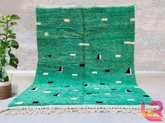 Bring a touch of global artistry into your home with this bohemian green Moroccan rug, a handmade Berber carpet woven with care by Moroccan artisans. Featuring rich emerald and olive tones, this wool rug is both luxurious and durable, ideal for high-traffic areas. The abstract patterns and organic imperfections tell a story of traditional craftsmanship, making each rug one-of-a-kind. Whether used as a statement floor piece or a cozy accent, this vintage-inspired rug complements mid-century, boho, or minimal
