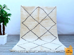 Elevate your interior with this bohemian Moroccan wool rug, a stunning handwoven Berber carpet that blends artistry and functionality. Featuring intricate tribal patterns in neutral tones, this vintage-inspired rug adds character and warmth to any room. The high-quality wool ensures a soft, luxurious feel, while the durable hand-knotted construction promises long-lasting beauty. Perfect for boho, eclectic, or mid-century modern spaces, this authentic tribal rug makes a striking statement in living areas, be