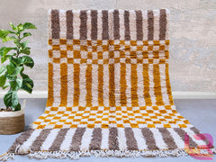 Bring timeless elegance to your home with this handmade Moroccan Orange Checkered Area Rug, a stunning Beni Ourain Berber carpet crafted with premium sheep wool. Featuring a bold checkered pattern in warm orange and white tones, this rug adds a bohemian yet sophisticated touch to any living space. Perfect for modern, boho, or eclectic interiors, it’s soft, durable, and custom-sized to fit your needs. Each rug is authentically handwoven by Berber artisans, ensuring unique craftsmanship. Free shipping makes i
