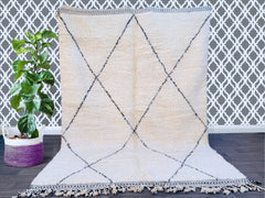 Discover the timeless beauty of a handmade Moroccan Beni Ourain rug, crafted by Berber artisans using 100% pure wool. This authentic vintage rug features a soft, plush texture and a minimalist black-and-white diamond pattern, perfect for boho, modern, or rustic interiors. Available in custom sizes, this luxurious Berber carpet adds warmth and elegance to any space—ideal for living rooms, bedrooms, or home decor. Shop bohemian rugs online with free shipping options. A sustainable, ethically sourced piece tha