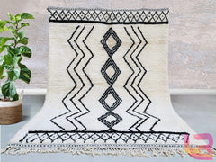 Elevate your home with a handmade Moroccan Beni Ourain rug, crafted from natural wool by skilled Berber artisans. This authentic tribal rug features a soft, plush texture and a timeless black-and-white geometric design, perfect for modern and boho interiors. Each custom Moroccan carpet is hand-knotted, ensuring durability and unique artistry. Whether used as a living room centerpiece or a bedroom accent, this wool Berber rug adds warmth and elegance. Free shipping available for a seamless shopping experienc