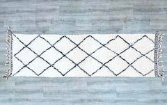 Elevate your space with this authentic handmade Moroccan Beni Ourain runner rug, crafted from 100% natural wool for durability and softness. Measuring 2.8 ft x 9.5 ft, this vintage-style Berber carpet features traditional geometric patterns in neutral tones, perfect for hallways, living rooms, or entryways. The handwoven design showcases intricate tribal motifs, adding a bohemian and rustic charm to any interior. Ideal for high-traffic areas, this wool runner rug is both plush and easy to clean, blending se