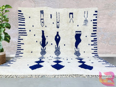 Bring timeless elegance into your home with this handmade Moroccan Blue Beni Ourain rug, a stunning piece of authentic Berber craftsmanship. Woven by skilled artisans using premium wool, this rug features a soft ivory and deep blue geometric design, perfect for adding a bohemian touch to any space. The natural wool fibers provide durability and a plush feel underfoot, making it ideal for living rooms, bedrooms, or cozy reading nooks. Each rug is hand-knotted, ensuring a unique, one-of-a-kind piece that refl