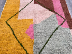 Bring a vibrant touch of Moroccan craftsmanship into your home with this handmade Boujaad rug in striking pink and orange hues. Measuring 9'5x6'5 ft (2.9x2 m), this authentic Berber rug is woven by skilled artisans using 100% natural sheep wool, ensuring both durability and softness underfoot. The Bidouh design features bold geometric patterns and a rich color palette, making it a perfect statement piece for bohemian, eclectic, or modern interiors. Whether placed in a living room, bedroom, or entryway, this