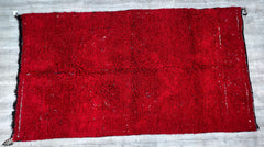 Bring rustic elegance into your home with this oversized vintage Beni Mguild Moroccan rug. Handwoven from natural wool, this 6x12 ft carpet features a deep red base with subtle tribal markings, embodying the nomadic Berber tradition. The thick, high-pile weave offers unmatched softness underfoot, ideal for cozy living rooms or bedrooms. Its distressed vintage finish adds character, while the neutral undertones blend seamlessly with various color schemes. Perfect for boho, farmhouse, or global-inspired inter