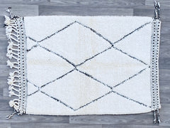 Elevate your décor with this exquisite Beni Ourain rug, a hand-knotted masterpiece from Morocco’s Atlas Mountains. Made from premium undyed wool, this plush, high-pile rug offers unmatched softness underfoot, ideal for cozy living rooms or chic bedrooms. The neutral white and ivory tones with subtle black tribal patterns blend seamlessly into boho, modern farmhouse, or eclectic interiors. Available in multiple sizes (4x6, 5x8, 8x11 ft), this authentic Berber rug is ethically crafted by skilled artisans, ens