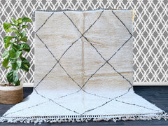 Indulge in the luxurious texture of this authentic Beni Ourain wool rug, a stunning centerpiece for any boho-inspired interior. Handwoven by Moroccan artisans, this plush carpet showcases intricate geometric motifs in a classic cream and black palette, offering both comfort and sophistication. The high-quality natural wool provides insulation and softness underfoot, making it ideal for cozy bedrooms or stylish living areas. Its versatile design complements Scandinavian, eclectic, or farmhouse aesthetics, ad