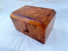 Discover the perfect blend of tradition and sophistication with this handmade wooden jewelry box, crafted from rich Thuya burl wood. Designed with a two-tier storage system, it provides organized space for all your jewelry essentials. The intricate Moroccan craftsmanship shines through in the detailed woodwork, while the mother-of-pearl inlays add a touch of opulence. A built-in mirror and secure locking mechanism make it both functional and elegant. Whether displayed on a vanity or dresser, this decorative