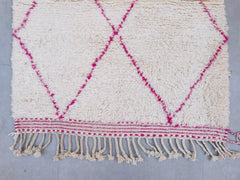 A fusion of tradition and contemporary style, this Moroccan wool rug showcases the finest Beni Ourain weaving techniques. The soft pink hues and intricate tribal patterns create a warm, inviting atmosphere, perfect for cozy living spaces. Handwoven by Berber artisans, each rug tells a story through its unique diamond motifs and textured wool. Whether used as a statement piece in a minimalist setting or layered for a boho-chic look, this rug effortlessly enhances any decor. The natural wool fibers provide du