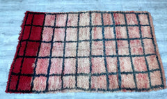 Elevate your space with this striking red and black checkered Moroccan runner, handwoven by Berber weavers using traditional techniques. The 3x6-foot size makes it ideal for hallways, kitchens, or entryways, while the bold grid pattern adds a graphic, modern touch to tribal decor. Crafted from natural cotton or wool, this rug is both sturdy and soft underfoot. The vintage wash enhances its rustic charm, blending seamlessly with eclectic, Scandinavian, or contemporary interiors. A versatile and eye-catching 