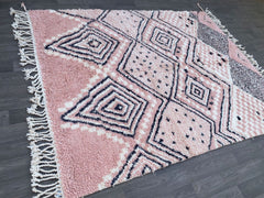 Bring a soft, cozy touch to your space with this Scandinavian-inspired pink area rug, featuring a handwoven Berber wool design in delicate salmon and neutral tones. The minimalist geometric patterns add subtle elegance, making it ideal for modern, boho, or eclectic interiors. Made from natural, high-quality wool, this rug is soft underfoot and built to last. Its versatile color palette complements neutral décor while adding a gentle pop of warmth. Whether used in a nursery, bedroom, or living area, this han