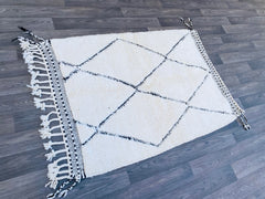 Discover the artisanal beauty of this handwoven Beni Ourain rug, a true Berber treasure from Morocco. Featuring a soft, shaggy texture and organic ivory-and-black geometric motifs, this rug adds warmth and character to any room. Perfect for boho, minimalist, or mid-century modern spaces, it’s crafted from natural, eco-friendly wool by generations-old weaving techniques. Choose from classic sizes (3x5 ft, 5x8 ft, 6x9 ft) or request a custom-made rug for a perfect fit. Whether used as a living room centerpiec