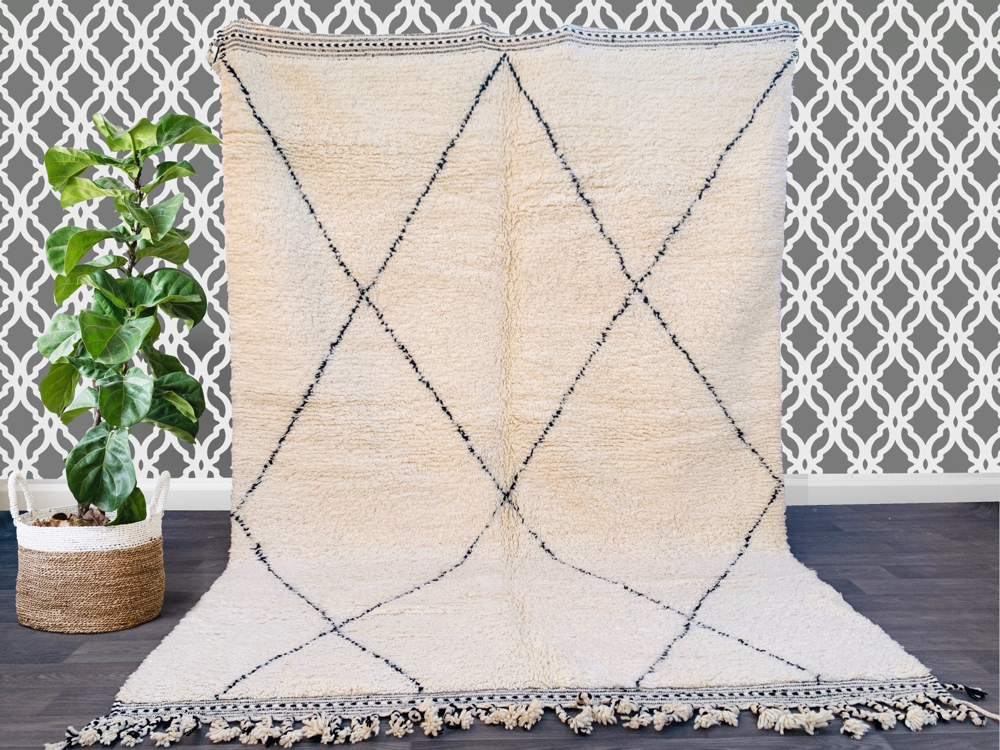 Enhance your space with a vintage Moroccan Berber rug, a stunning handmade wool carpet featuring intricate tribal motifs. Crafted in the classic Beni Ourain tradition, this rug boasts a soft, high-pile texture and an organic, undyed wool finish. The geometric black diamond patterns on a creamy white background create a striking contrast, making it a versatile centerpiece for any room. Perfect for boho-chic, Scandinavian, or eclectic interiors, this authentic Azilal-style rug adds texture and warmth to floor