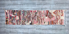 This authentic vintage Moroccan Boujaad runner rug (2.3 ft x 9.2 ft) is a stunning handmade piece, crafted by Berber artisans using traditional techniques. Woven from high-quality wool, it features a geometric tribal design with rich, faded colors, perfect for hallways, entryways, or bohemian-inspired spaces. The rug’s distressed texture and earthy tones add warmth and character to any room. Each piece is unique, showcasing the artistry of Moroccan craftsmanship. Ideal for vintage lovers, this durable, one-