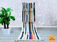 Bring global charm to your floors with this 3x10 FT Moroccan runner rug, showcasing a handwoven Beni Ourain pattern in bold, multicolored wool. Ideal for high-traffic areas, this durable hallway carpet blends Bohemian flair with traditional Berber craftsmanship. The intricate tribal motifs and plush texture make it a standout piece for minimalist or maximalist décor. Choose from vintage-bound finishes, Azilal-inspired designs, or custom color schemes to match your aesthetic. Each rug is ethically handmade, 