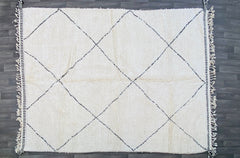 Bring the rich heritage of Moroccan craftsmanship into your home with this vintage tribal Berber rug, meticulously handwoven from pure wool. The intricate diamond and zigzag patterns reflect centuries-old Berber traditions, creating a captivating focal point in any room. Its durable, high-pile construction ensures long-lasting beauty, while the neutral tones effortlessly enhance bohemian, mid-century, or eclectic decor styles. Whether used as a statement floor covering or a wall hanging, this authentic Moro