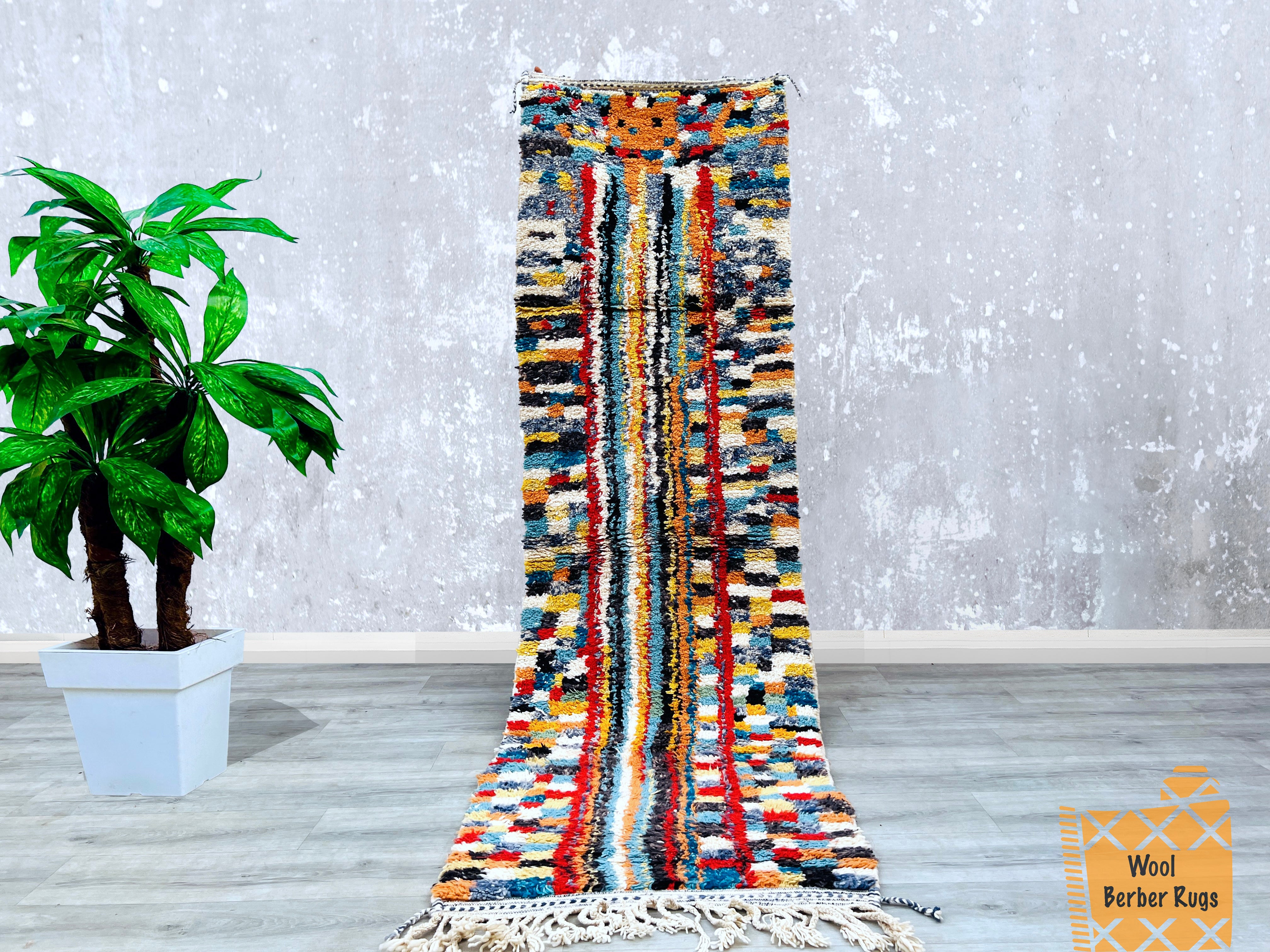 Elevate your home decor with this handmade Moroccan runner rug, showcasing a striking multicolored pattern in a 2.8 ft x 9.5 ft size. Designed with vintage Berber influences, this Boho-inspired carpet features Azilal tribal motifs, blending deep browns, creams, and pops of color for a dynamic look. The Beni Ourain-style weaving ensures a plush, durable texture, perfect for high-traffic areas like hallways or entryways. Whether used as a statement piece in a modern living room or a cozy bedroom accent, this 